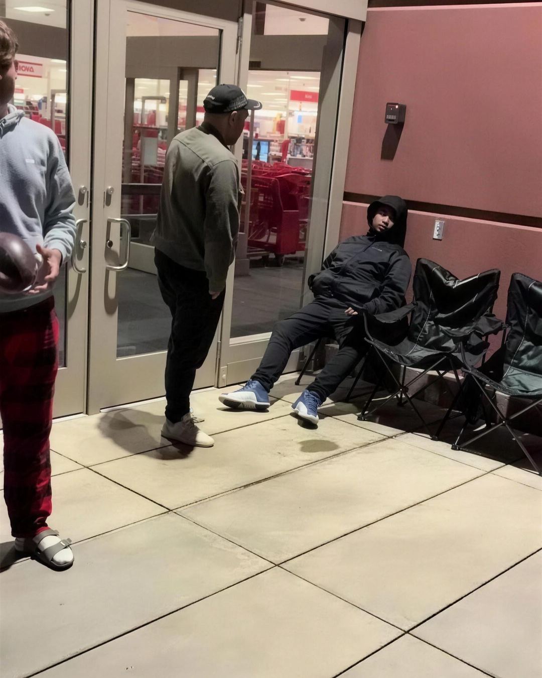 People waiting in camping chairs outside a store at night